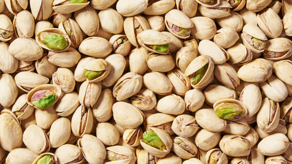A stack of whole and cracked pistachios, representing the successful agricultural and marketing blueprint that the American chestnut industry is working to follow.