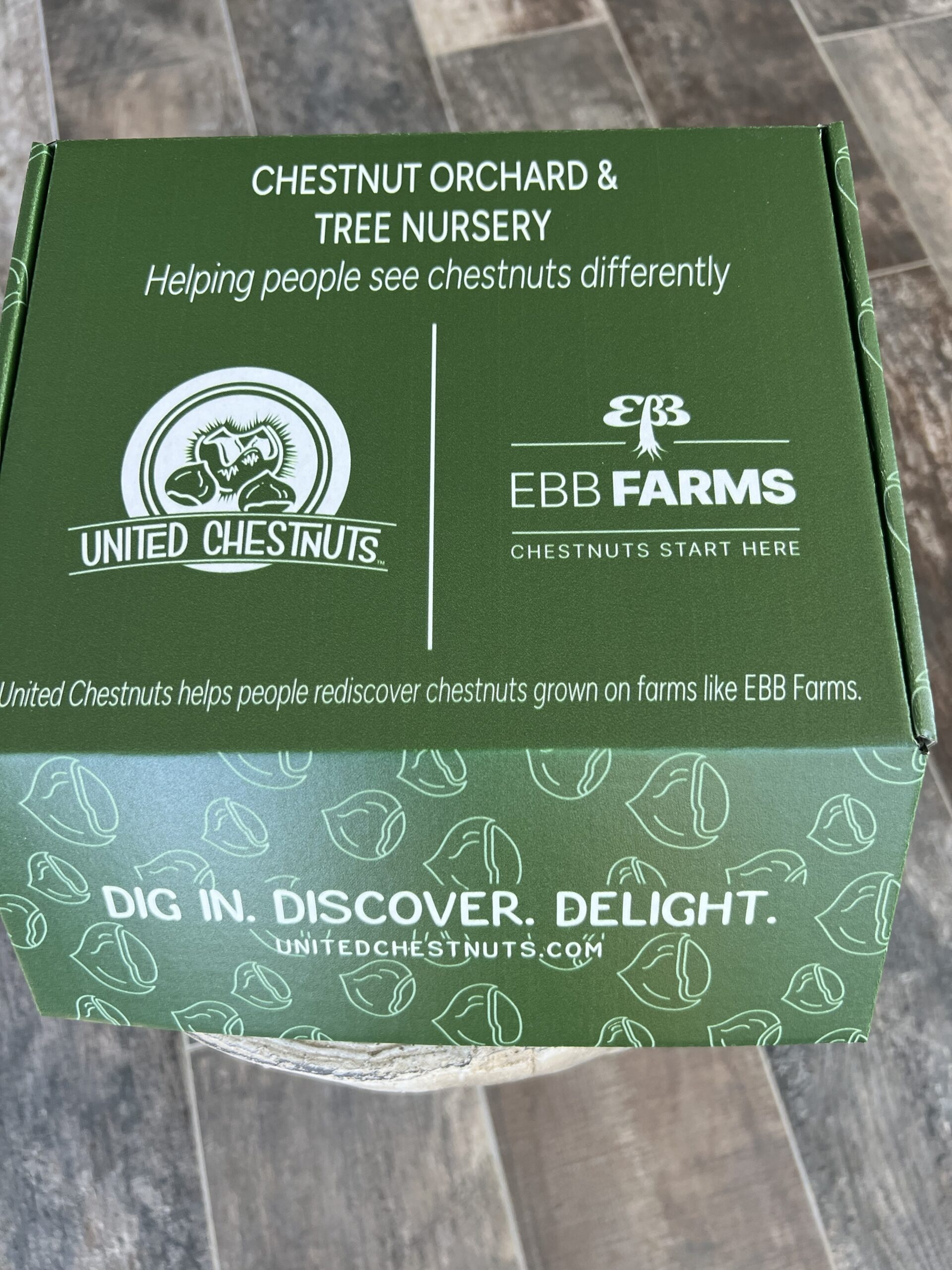 Closed box of premium chestnut seed nuts for planting from EBB Farms, with mesh bag of nuts and United Chestnuts Academy branding.